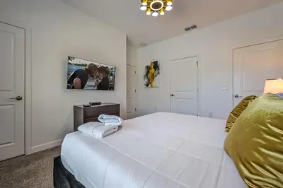 a bedroom with a large white bed with a tv on the wall at Casa com Piscina Privativa a 10 Min da Disney in Kissimmee