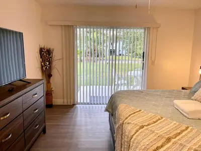a bedroom with a bed and a dresser and a sliding glass door at Grand Superior 3BR Condo Apartment Near Disney Parks in Kissimmee