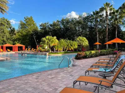 a large swimming pool with chairs and umbrellas at Grand Emerald 3BR Townhouse Near Disney Parks in Kissimmee