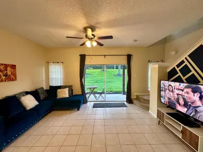 a living room with a couch and a flat screen tv at Grand Emerald 3BR Townhouse Near Disney Parks in Kissimmee