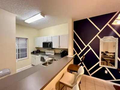 a kitchen with white cabinets and a black wall at Grand Emerald 3BR Townhouse Near Disney Parks in Kissimmee
