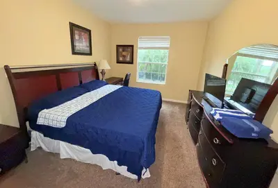 a bedroom with a blue bed and a television at King Room with Bathroom near Convention Center & Epic Universe in Orlando