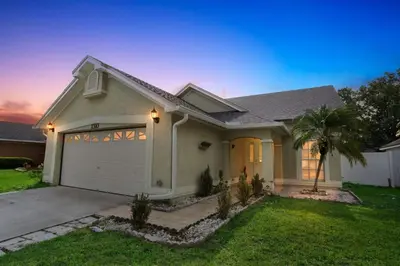 a house with a garage and a palm tree at Orlando Family 4BR | 10 Min to SeaWorld in Orlando