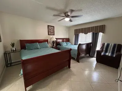 a bedroom with a bed and a couch and a ceiling fan at Orlando Family 4BR | 10 Min to SeaWorld in Orlando