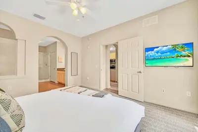 a white bedroom with a bed and a ceiling fan at Stylish 2BR Retreat w Pool Sauna in Orlando