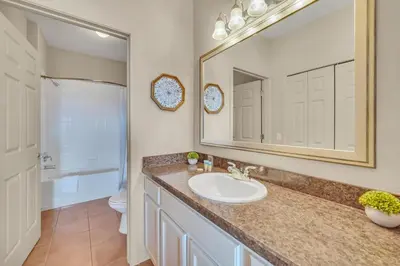 a bathroom with a sink and a mirror and a toilet at Upstay - Condo - Hot Tub & Pool in Orlando