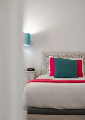 a white bed with a pink and green pillow on it at Fabulous Condo at World Quest Resort Disney area in Orlando