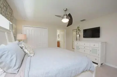 a bedroom with a white bed and a tv at Casa de 4 Quartos com Piscina Privativa in Kissimmee