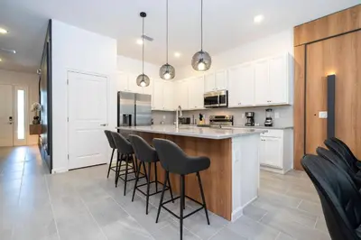 a kitchen with white cabinets and bar stools at NEW Paradiso Grande Disney Themed Cinema5827 in Orlando
