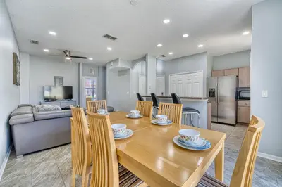 a kitchen and dining room with a wooden table and chairs at Stylish Townhome Close to Disney Parks in Kissimmee