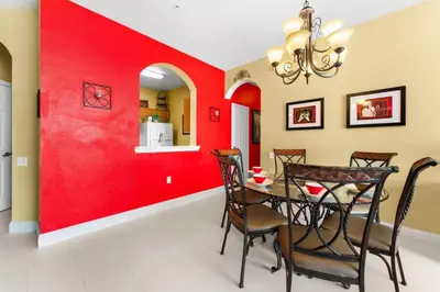 a dining room with red walls and a table with chairs at Windsor Palms Mickey Themed Condo, Pool, By Disney in Kissimmee