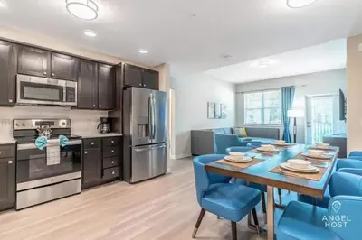 a kitchen and dining room with a table and blue chairs at Vista Cay Resort in Orlando