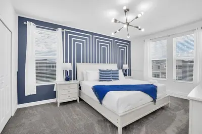 a bedroom with a white bed and blue accent wall at Disney Nearby! Private Pool, Movie Theater & Themed Rooms – Storey Lake Resort! in Kissimmee