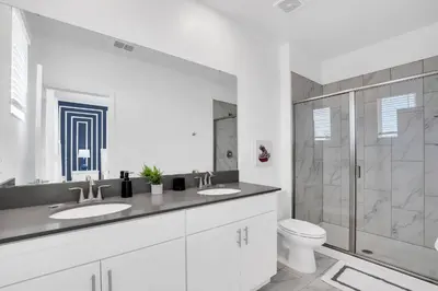 a white bathroom with two sinks and a shower at Disney Nearby! Private Pool, Movie Theater & Themed Rooms – Storey Lake Resort! in Kissimmee