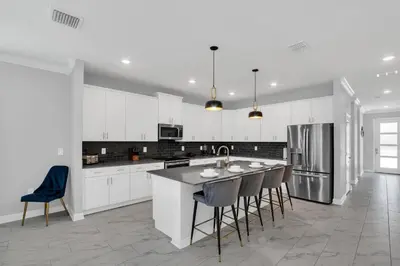a kitchen with white cabinets and a island with bar stools at Disney Nearby! Private Pool, Movie Theater & Themed Rooms – Storey Lake Resort! in Kissimmee