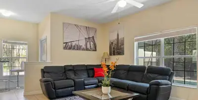 a living room with a black leather couch at Amazing 05 Bedrooms 4 Bathrooms Sleeps 14 in Kissimmee