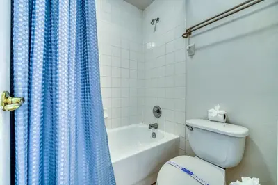 a bathroom with a toilet and a blue shower curtain at Private Pool Getaway Near Theme Parks in Kissimmee