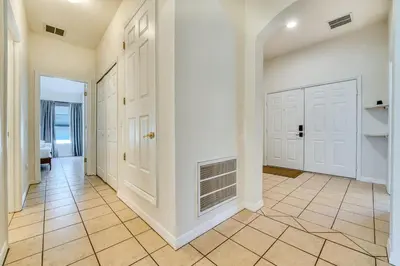 a hallway with white doors and a tile floor at Private Pool Getaway Near Theme Parks in Kissimmee