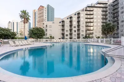 a large swimming pool with buildings in the background at Amazing 2 Bedrooms Nex to Universal in Orlando