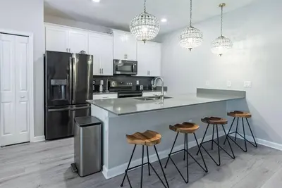 a kitchen with white cabinets and a counter with stools at Brand New 5 Bedrooms4 Baths At Storey Lake in Kissimmee