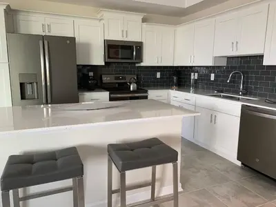 a kitchen with white cabinets and a large island with stools at Aqua Vista Gated Resort Style Community in Kissimmee