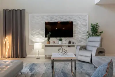 a living room with a couch and a tv at Brand New 5 Bedrooms5Baths At Storey Lake in Kissimmee