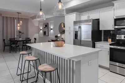 a kitchen with white cabinets and a island with bar stools at NEW Cozy 2 Bedrooms2Baths At Storey Lake in Kissimmee
