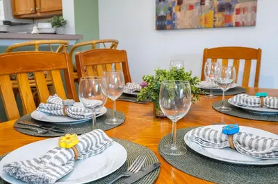 a wooden table with plates and wine glasses on it at Charming Vacation Home 9 miles From Disney 1065 in Kissimmee