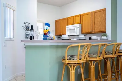 a kitchen with wooden cabinets and a counter with stools at Charming Vacation Home 9 miles From Disney 1065 in Kissimmee