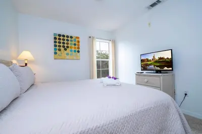 a white bedroom with a white bed and a television at Charming Vacation Home 9 miles From Disney 1065 in Kissimmee