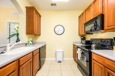 a kitchen with wooden cabinets and a clock on the wall at Beautiful Deluxe Condo, Vista Cay - 3015 in Orlando