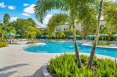 a resort swimming pool with palm trees and umbrellas at Beautiful Modern Condo, Near the Parks! - 3021 in Orlando