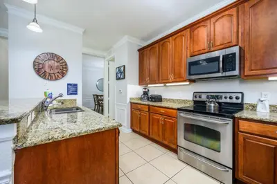 a kitchen with wooden cabinets and stainless steel appliances at Epic Universe 4 Bedroom Plus, Lake View Condo, Vista Cay-1008 in Orlando