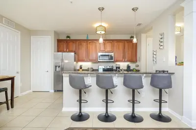 a kitchen with three bar stools in front of a counter at Epic Universe Vacation Condo, Vista Cay - 2017 in Orlando