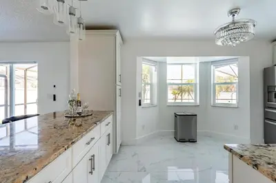 a kitchen with white cabinets and marble counter tops at Villa Resort Club in Kissimmee