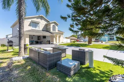 a house with a grill and palm trees at Villa Resort Club in Kissimmee