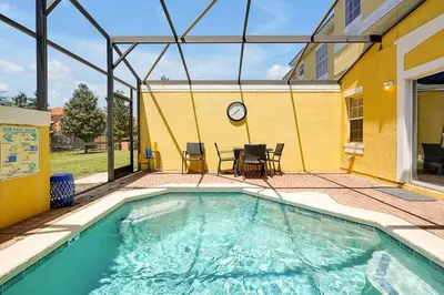 a swimming pool with a table and chairs and a clock at Encantada Resort 10 minutes to Disney w/ Pool in Kissimmee