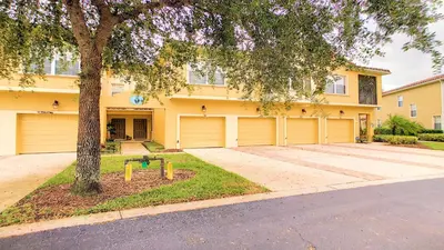 a yellow house with a tree in front of it at Oakwater Fountain View 3BR Home, Pool, By Disney in Orlando