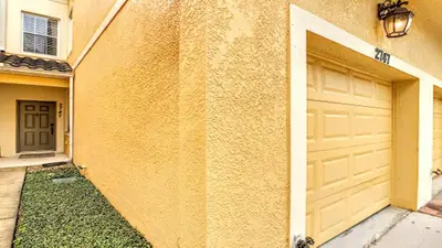 a building with a garage door and a driveway at Oakwater Fountain View 3BR Home, Pool, By Disney in Orlando