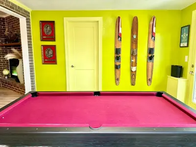 a pool table in a room with skis on the wall at Happy Palette Home Close to downtown Fenced yard in Sanford