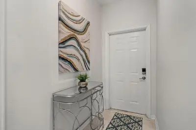 a hallway with a table and a painting on the wall at Cozy & Stylish 2BR Condo Prime Storey Lake Spot in Kissimmee