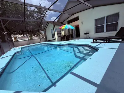 a swimming pool with an umbrella on top of it at 4701-Lake Berkley villa- Renovated 3 bed in Kissimmee