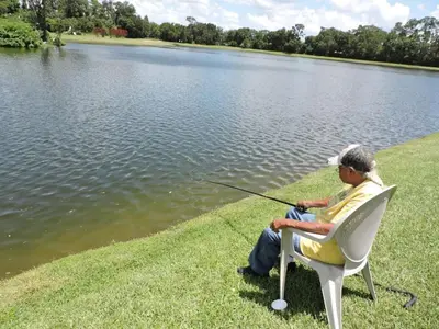 a man sitting in a chair fishing on a lake at 4701-Lake Berkley villa- Renovated 3 bed in Kissimmee