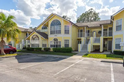 a yellow house with a car parked in a parking lot at Disney-Area Kissimmee 3BR | Community Pool in Kissimmee