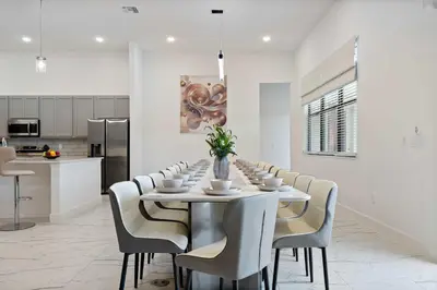 a white dining room with a long table and chairs at Grand 15-Bedroom Villa -Magical Themes Pool & Game Loft Lakeview in Kissimmee