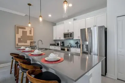 a kitchen with a large counter with chairs and a refrigerator at 2416 Luxo & Magia: Casa com Piscina no Storey Lake! in Kissimmee