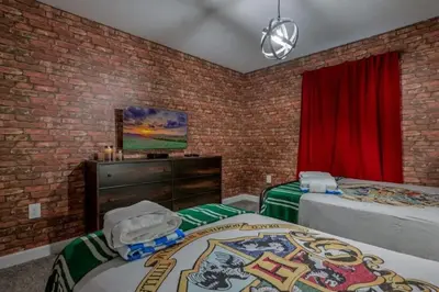 a bedroom with two beds and a brick wall at 2416 Luxo & Magia: Casa com Piscina no Storey Lake! in Kissimmee