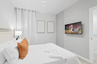 a white bedroom with a bed and a tv on the wall at Luxury Paradise in Orlando Best Location in Orlando
