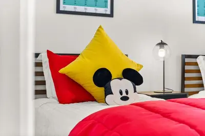 a stuffed mickey mouse pillow sitting on a bed at Family favorite Disney pool home in Kissimmee