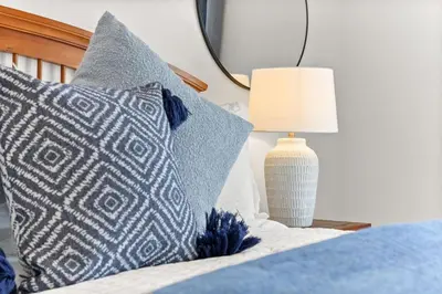 a bed with blue and white pillows and a lamp at Family favorite Disney pool home in Kissimmee